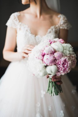 Gelin çiçekli büyük ve güzel bir düğün buketi tutuyor..