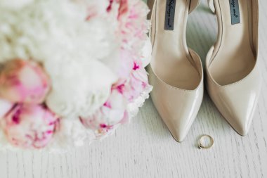 Bir çift zarif ve şık gelin ayakkabısı içinde güller ve diğer çiçeklerle dolu bir buket..