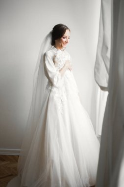 Cüppeli muhteşem gelin bir odada düğün töreni için poz veriyor ve hazırlanıyor..