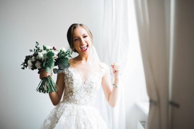 Lüks bir gelin, bir kız buketle poz veriyor ve gülümsüyor..