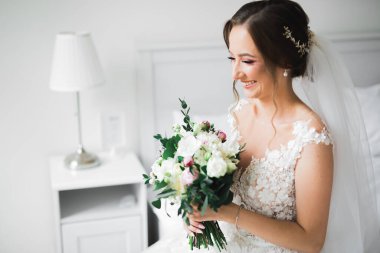 Lüks bir gelin, bir kız buketle poz veriyor ve gülümsüyor..