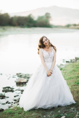Nehir kenarında poz veren zarif beyaz elbiseli güzel esmer gelin..