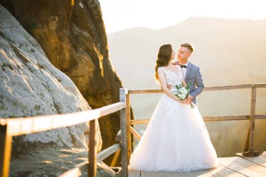 Doğadaki düğün çifti birbirine sarılıyor. Beyaz elbiseli güzel bir kız. Takım elbiseli adam.