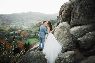 Dağların arka planında sevgi dolu bir koca ve kadın. Sevgili çift duygusal olarak vakit geçirir..