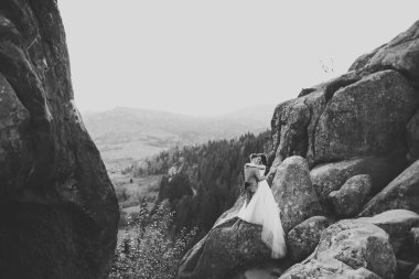 Dağların arka planında sevgi dolu bir koca ve kadın. Sevgili çift duygusal olarak vakit geçirir..