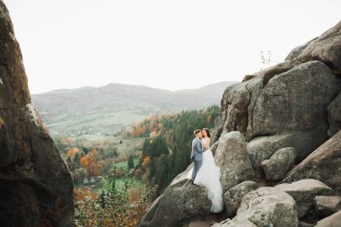 Dağların arka planında sevgi dolu bir koca ve kadın. Sevgili çift duygusal olarak vakit geçirir..