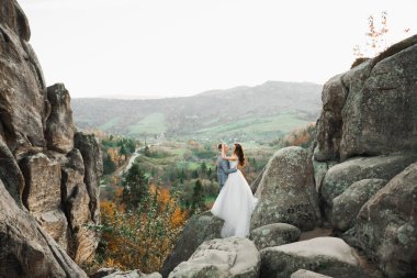 Dağların arka planında sevgi dolu bir koca ve kadın. Sevgili çift duygusal olarak vakit geçirir..