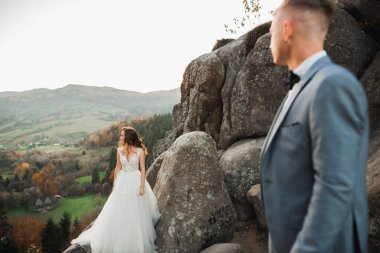 Dağların arka planında sevgi dolu bir koca ve kadın. Sevgili çift duygusal olarak vakit geçirir..