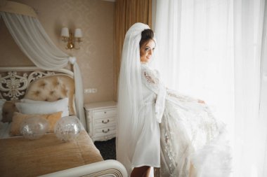 Cüppeli muhteşem gelin bir odada düğün töreni için poz veriyor ve hazırlanıyor..