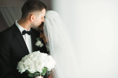 Güzel, genç bir çift ellerinde çiçeklerle poz veriyorlar..