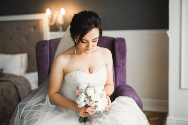 Çekici gelinin portresi, uzun saçlı, büyük buketli poz veren..