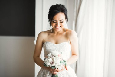 Lüks bir gelin, bir kız buketle poz veriyor ve gülümsüyor..