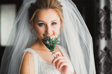 Cüppeli muhteşem gelin bir odada düğün töreni için poz veriyor ve hazırlanıyor..