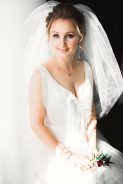 Cüppeli muhteşem gelin bir odada düğün töreni için poz veriyor ve hazırlanıyor..