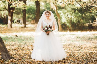 Gelin çiçekli büyük ve güzel bir düğün buketi tutuyor..