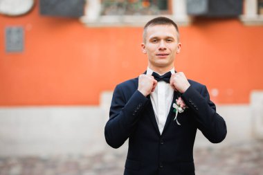 Yaka çiçeğiyle poz veren mutlu yakışıklı damat..