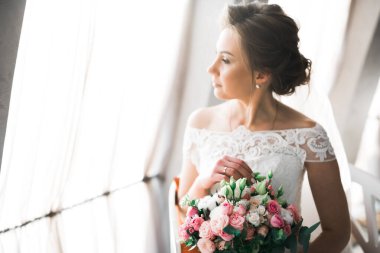 Gelin çiçekli büyük ve güzel bir düğün buketi tutuyor..