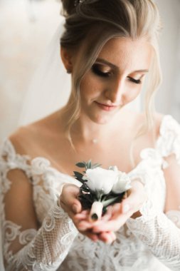 Zarif beyaz elbiseli güzel gelin elinde bir buket çiçek tutuyor..