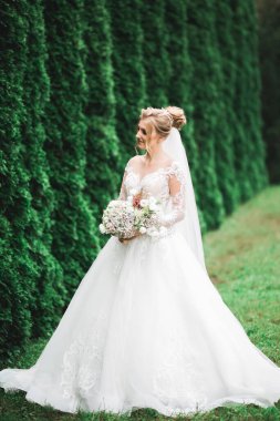 Lüks bir gelin, bir kız buketle poz veriyor ve gülümsüyor..