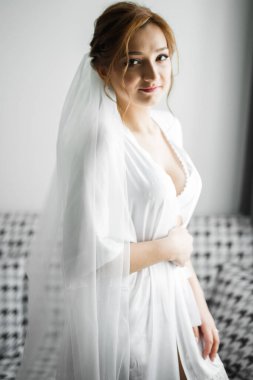 Cüppeli muhteşem gelin bir odada düğün töreni için poz veriyor ve hazırlanıyor..