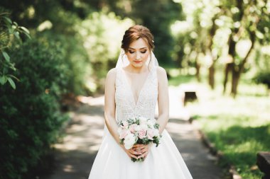 Gelin çiçekli büyük ve güzel bir düğün buketi tutuyor..