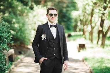 Yaka çiçeğiyle poz veren mutlu yakışıklı damat..