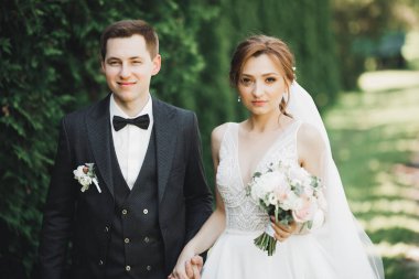 Mutlu düğün çift büyüleyici damat ve mükemmel gelin parkta poz.