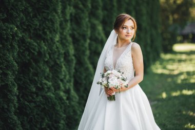 Gelin çiçekli büyük ve güzel bir düğün buketi tutuyor..