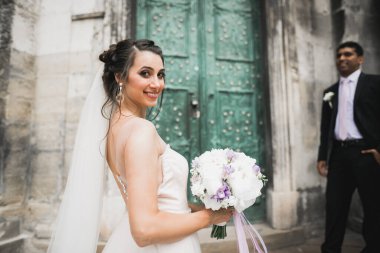 Güzel, mutlu bir düğün çifti, güzel şehirde uzun beyaz elbiseli bir gelin..