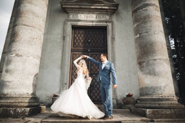 Güzel bir düğün çifti yeni evlendi ve eski binanın yakınında dans ediyor..