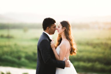 Doğadaki düğün çifti birbirine sarılıyor. Beyaz elbiseli güzel bir kız. Takım elbiseli adam.