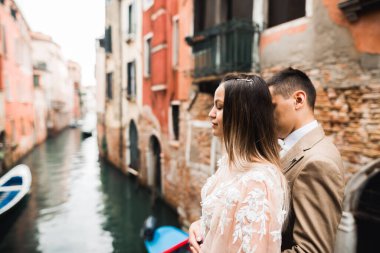 Doğadaki düğün çifti birbirine sarılıyor. Beyaz elbiseli güzel bir kız. Takım elbiseli adam. Venedik, İtalya.