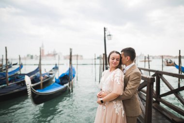 Doğadaki düğün çifti birbirine sarılıyor. Beyaz elbiseli güzel bir kız. Takım elbiseli adam. Venedik, İtalya.