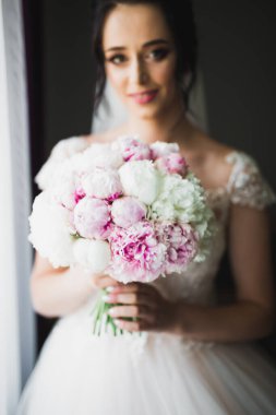 Gelin çiçekli büyük ve güzel bir düğün buketi tutuyor..