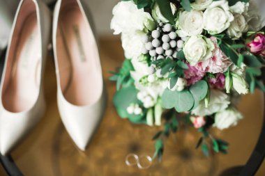 Bir çift zarif ve şık gelin ayakkabısı ile bir buket gül ve diğer çiçeklerle.
