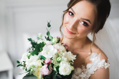 Lüks bir gelin, bir kız buketle poz veriyor ve gülümsüyor..