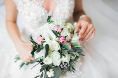 Gelin çiçekli büyük ve güzel bir düğün buketi tutuyor..
