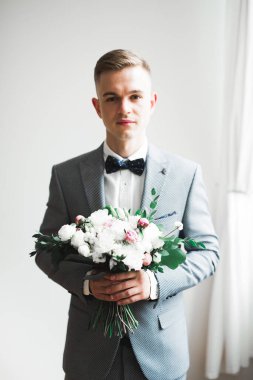 Yaka çiçeğiyle poz veren mutlu yakışıklı damat..