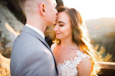 Doğadaki düğün çifti birbirine sarılıyor. Beyaz elbiseli güzel bir kız. Takım elbiseli adam.