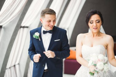 Büyük pencerelerin yanında dans eden mutlu yeni evliler..