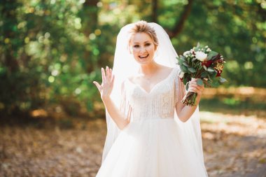 Lüks bir gelin, bir kız buketle poz veriyor ve gülümsüyor..