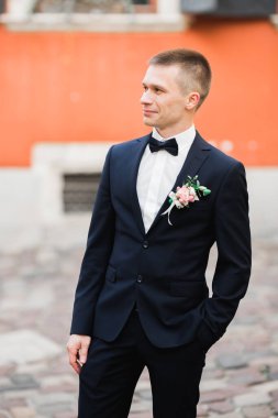 Yaka çiçeğiyle poz veren mutlu yakışıklı damat..