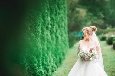 Lüks bir gelin, bir kız buketle poz veriyor ve gülümsüyor..