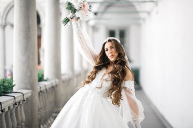 Çekici gelinin portresi, uzun saçlı, büyük buketli poz veren..