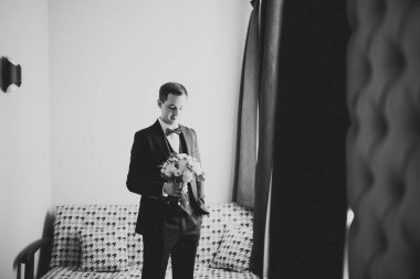 Güzel adam, damat elinde çiçeklerle büyük ve güzel bir düğün buketi tutuyor.