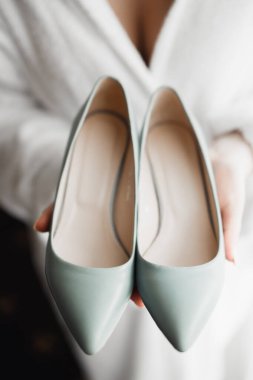 Zarif beyaz elbiseli güzel gelin ellerinde düğün ayakkabıları tutuyor..