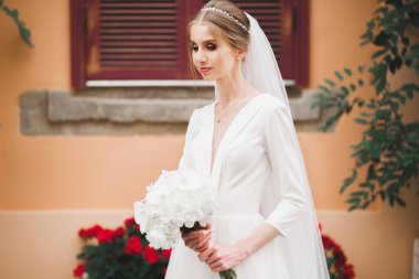 Lüks bir gelin, bir kız buketle poz veriyor ve gülümsüyor..