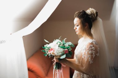 Gelin çiçekli büyük ve güzel bir düğün buketi tutuyor..