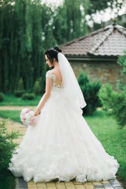 Lüks bir gelin, bir kız buketle poz veriyor ve gülümsüyor..