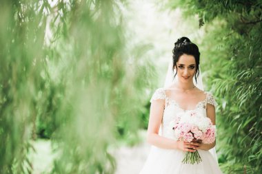 Lüks bir gelin, bir kız buketle poz veriyor ve gülümsüyor..